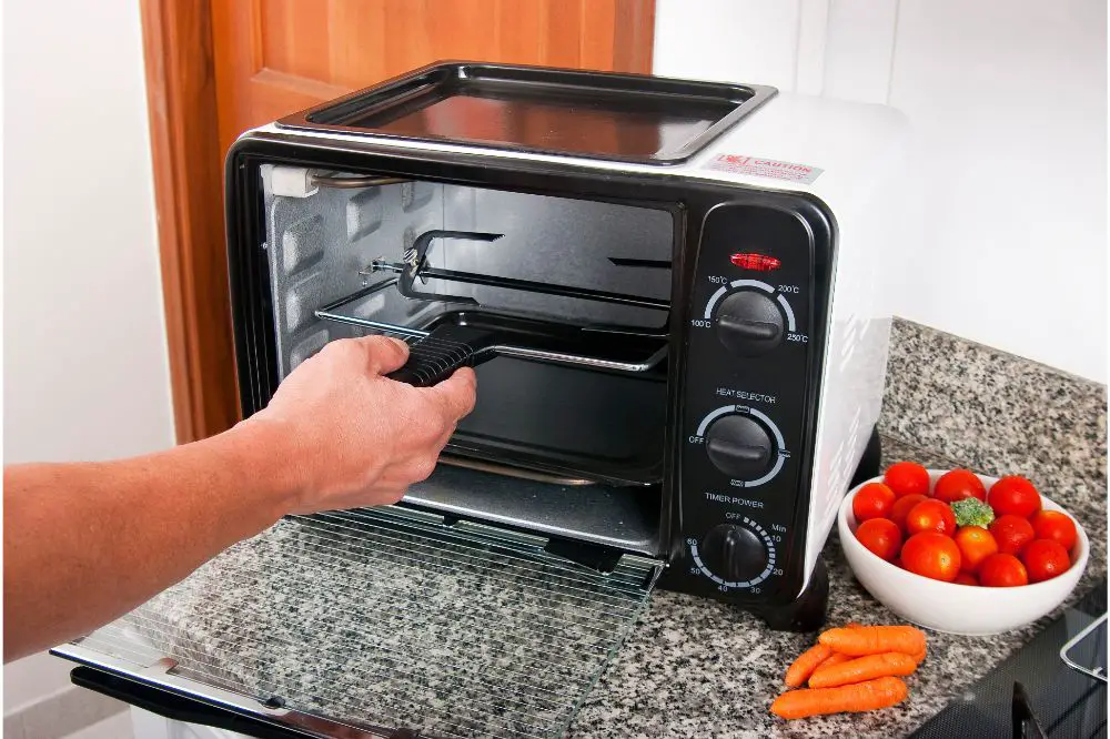 black and white color air fryer toster oven with bowl of tomatoes and carrots